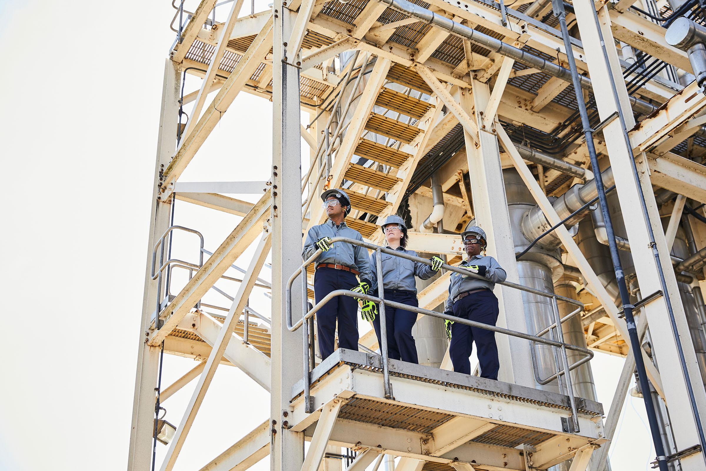 Three oil and gas workers in DH shirts and pants.